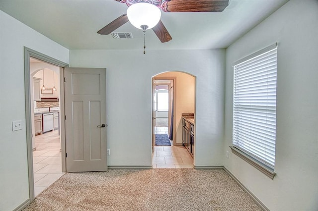 3024 Wakefield Rd, Edmond, OK 73034 - unfurnished bedroom featuring arched walkways, light tile patterned flooring, ensuite bathroom, and light carpet