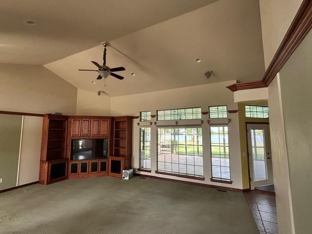 1608 Bentwater Dr, Kingfisher, OK 73750 - unfurnished living room featuring a ceiling fan, carpet floors, and high vaulted ceiling