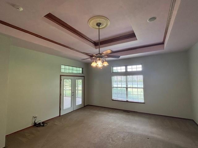 1608 Bentwater Dr, Kingfisher, OK 73750 - empty room featuring a raised ceiling, light carpet, french doors, a ceiling fan, and ornamental molding
