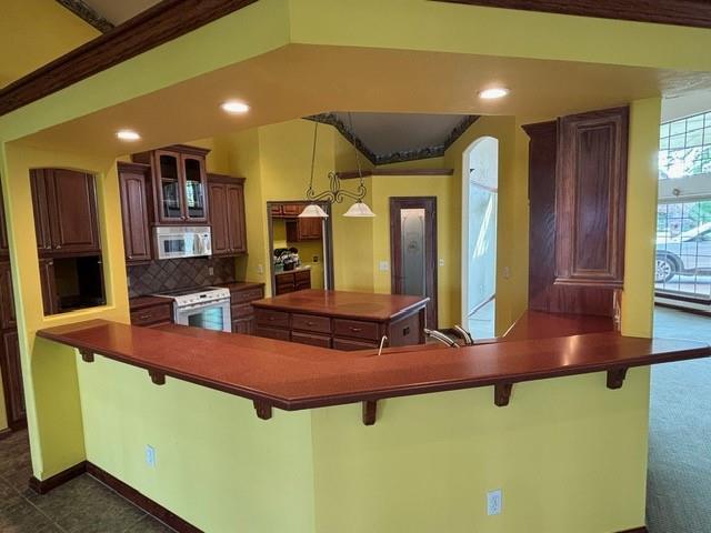 1608 Bentwater Dr, Kingfisher, OK 73750 - kitchen with white appliances, dark countertops, a kitchen bar, decorative backsplash, and recessed lighting