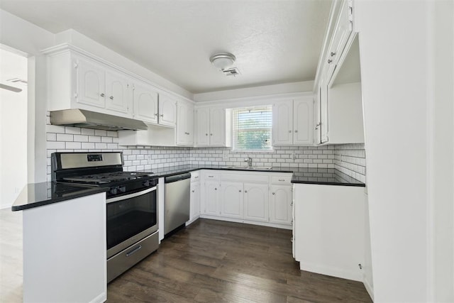 608 SW 9th St, Moore, OK 73160 - kitchen featuring stainless steel appliances, under cabinet range hood, dark countertops, a sink, and white cabinets