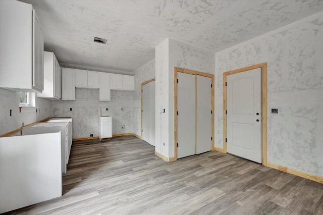 2807 N Lyon Dr, Oklahoma City, OK 73107 - kitchen with light wood-type flooring, white cabinets, and baseboards