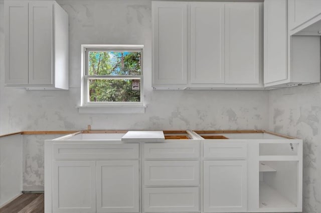 2807 N Lyon Dr, Oklahoma City, OK 73107 - kitchen with wallpapered walls, white cabinetry, and wood finished floors