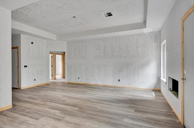 2807 N Lyon Dr, Oklahoma City, OK 73107 - unfurnished living room featuring a tray ceiling, wood finished floors, baseboards, and a fireplace