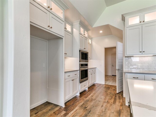 8525 Maple Creek Rd, Arcadia, OK 73007 - kitchen with stainless steel appliances, decorative backsplash, wood finished floors, vaulted ceiling, and white cabinets