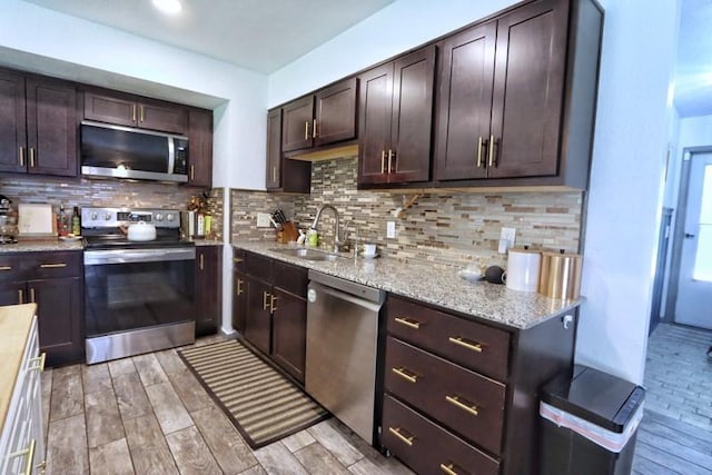 5704 N Warren Ave, Oklahoma City, OK 73112 - kitchen featuring stainless steel appliances, a sink, dark brown cabinetry, light wood-type flooring, and backsplash