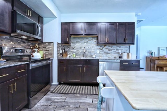 5704 N Warren Ave, Oklahoma City, OK 73112 - kitchen with stainless steel appliances, tasteful backsplash, a sink, and light stone countertops