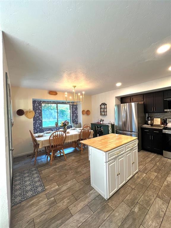 5704 N Warren Ave, Oklahoma City, OK 73112 - kitchen featuring stainless steel appliances, white cabinets, a chandelier, wood finish floors, and a textured ceiling