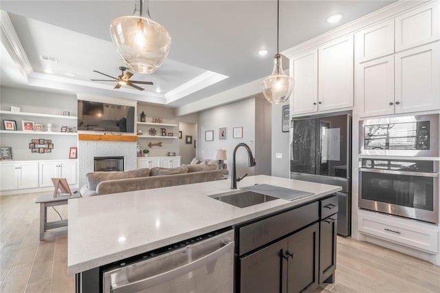 5808 Ledgestone Dr, Mustang, OK 73064 - kitchen with appliances with stainless steel finishes, a sink, a tray ceiling, a kitchen island with sink, and open floor plan
