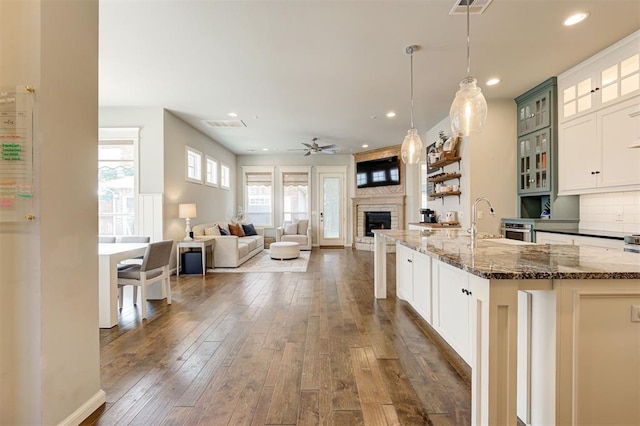 1508 Station St, Edmond, OK 73034 - kitchen with a large fireplace, ceiling fan, dark wood-style floors, recessed lighting, and dark stone countertops