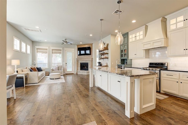 1508 Station St, Edmond, OK 73034 - kitchen featuring custom exhaust hood, gas stove, a fireplace, ceiling fan, and dark wood-type flooring