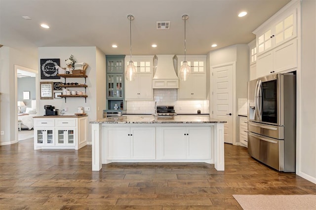 1508 Station St, Edmond, OK 73034 - kitchen with stainless steel fridge, custom exhaust hood, white cabinets, an island with sink, and recessed lighting