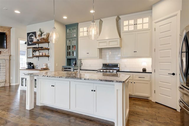 1508 Station St, Edmond, OK 73034 - kitchen featuring custom exhaust hood, stainless steel appliances, dark wood-type flooring, backsplash, and an island with sink