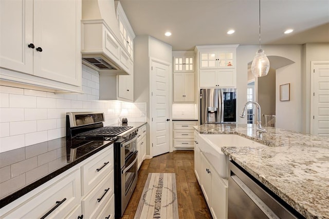 1508 Station St, Edmond, OK 73034 - kitchen featuring stainless steel appliances, custom exhaust hood, dark wood-style flooring, white cabinets, and decorative light fixtures