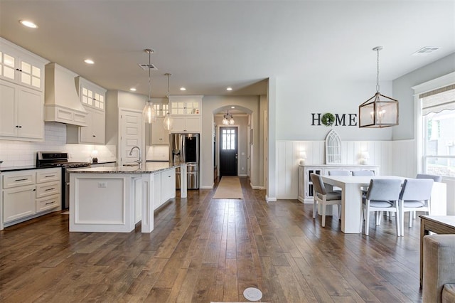 1508 Station St, Edmond, OK 73034 - kitchen featuring stainless steel appliances, premium range hood, arched walkways, dark wood finished floors, and white cabinets