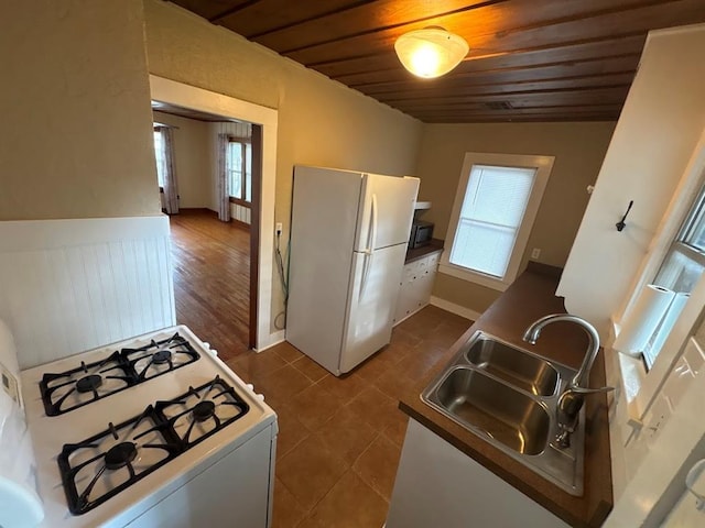 408 N Findlay St, Norman, OK 73071 - kitchen featuring white appliances, a sink, wooden ceiling, dark tile patterned floors, and baseboards