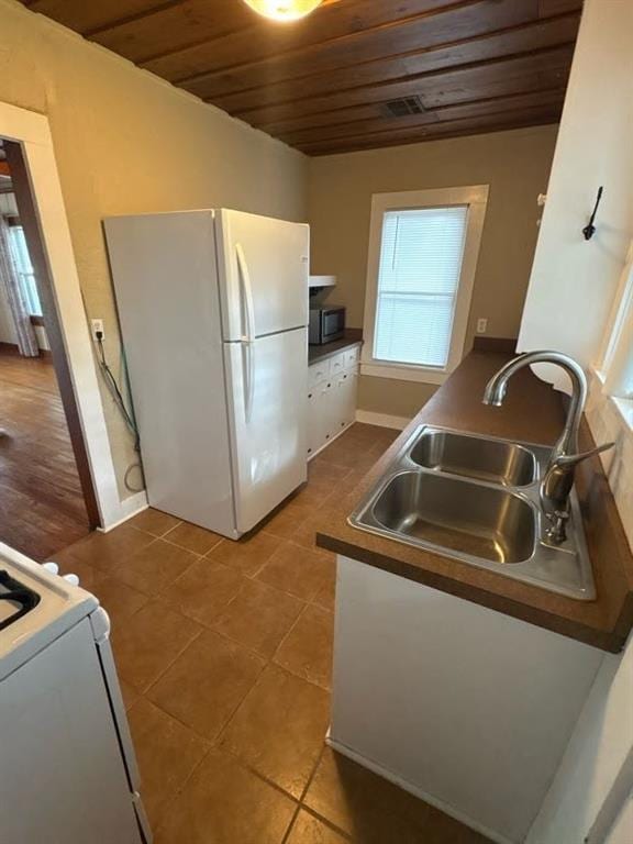 408 N Findlay St, Norman, OK 73071 - kitchen with freestanding refrigerator, wood ceiling, a sink, stainless steel microwave, and dark tile patterned floors