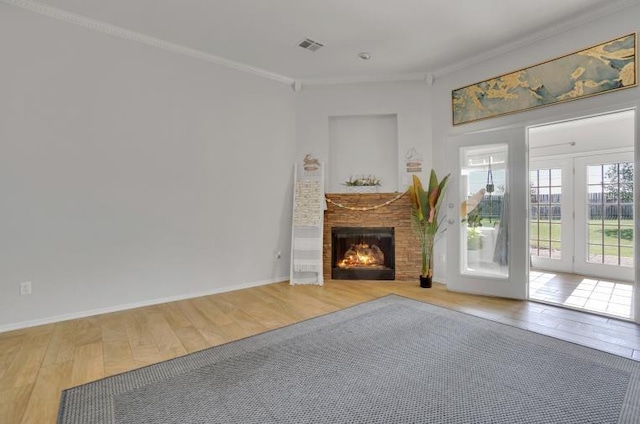 2 NW Havenshire Cir, Lawton, OK 73505 - unfurnished living room with light wood-style floors, crown molding, a lit fireplace, baseboards, and french doors