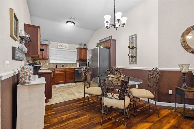 12329 SW 9th Ter, Yukon, OK 73099 - dining space with a chandelier, lofted ceiling, light tile patterned floors, and a wainscoted wall