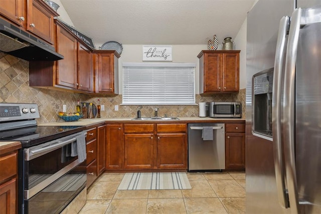 12329 SW 9th Ter, Yukon, OK 73099 - kitchen featuring appliances with stainless steel finishes, a sink, under cabinet range hood, tasteful backsplash, and light countertops