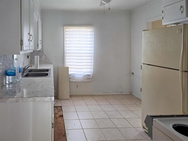 226 E Iowa St, Walters, OK 73572 - kitchen with freestanding refrigerator, a sink, light countertops, light tile patterned floors, and white cabinetry