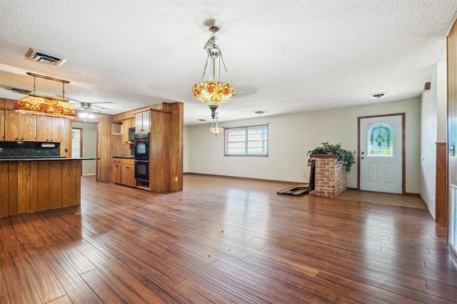 1317 S 58th St, Duncan, OK 73534 - unfurnished living room with a textured ceiling, dark wood finished floors, baseboards, and ceiling fan