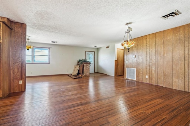1317 S 58th St, Duncan, OK 73534 - unfurnished living room featuring wooden walls, hardwood / wood-style floors, and a textured ceiling