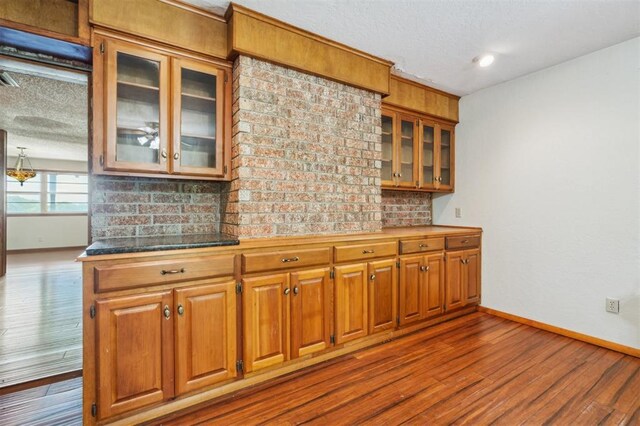 1317 S 58th St, Duncan, OK 73534 - kitchen with baseboards, dark wood finished floors, glass insert cabinets, brown cabinetry, and a textured ceiling