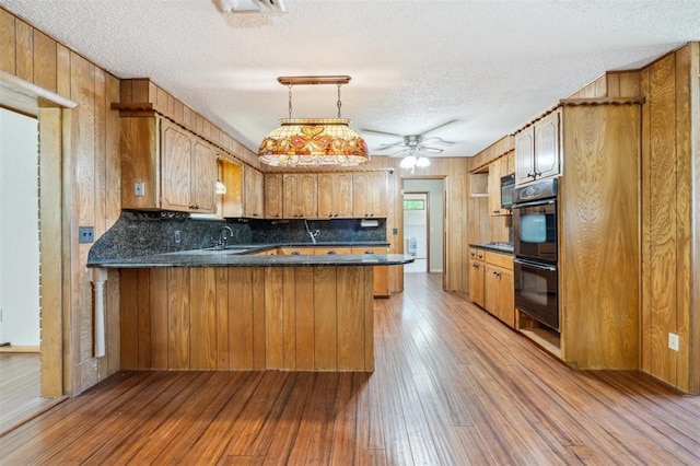 1317 S 58th St, Duncan, OK 73534 - kitchen with a textured ceiling, a peninsula, a sink, light wood-style flooring, and a ceiling fan