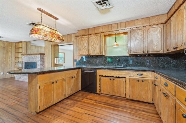 1317 S 58th St, Duncan, OK 73534 - kitchen with black dishwasher, a peninsula, a textured ceiling, decorative backsplash, and wood finished floors