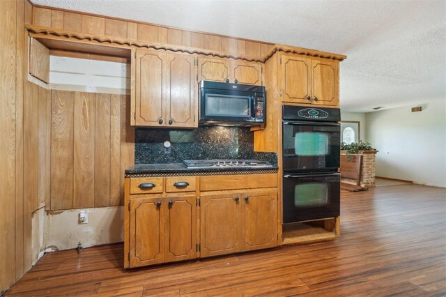 1317 S 58th St, Duncan, OK 73534 - kitchen with black appliances, wood finished floors, tasteful backsplash, a textured ceiling, and brown cabinetry