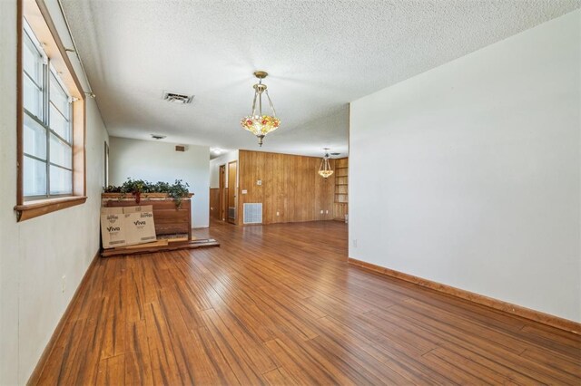 1317 S 58th St, Duncan, OK 73534 - unfurnished living room with wood finished floors, a textured ceiling, baseboards, and wood walls