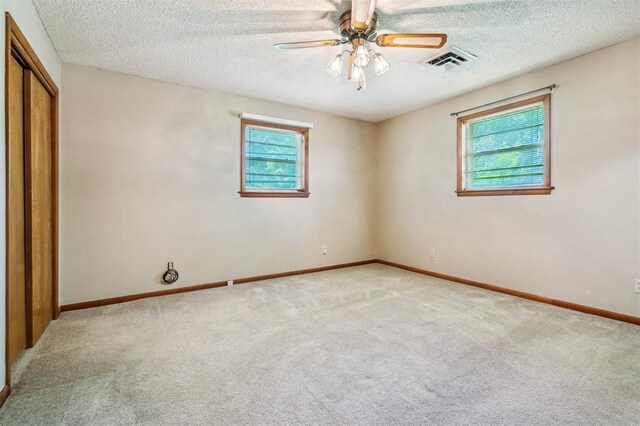 1317 S 58th St, Duncan, OK 73534 - unfurnished bedroom featuring multiple windows, light carpet, baseboards, a closet, and a textured ceiling