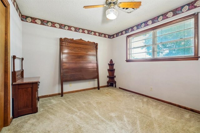 1317 S 58th St, Duncan, OK 73534 - unfurnished bedroom with light colored carpet, baseboards, a textured ceiling, and a ceiling fan