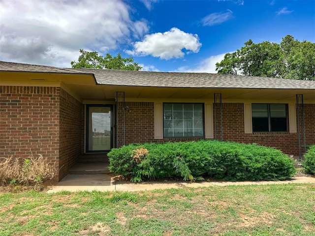 10190 County Road 1310, Fort Cobb, OK 73038 - view of exterior entry with brick siding, roof with shingles, and a lawn