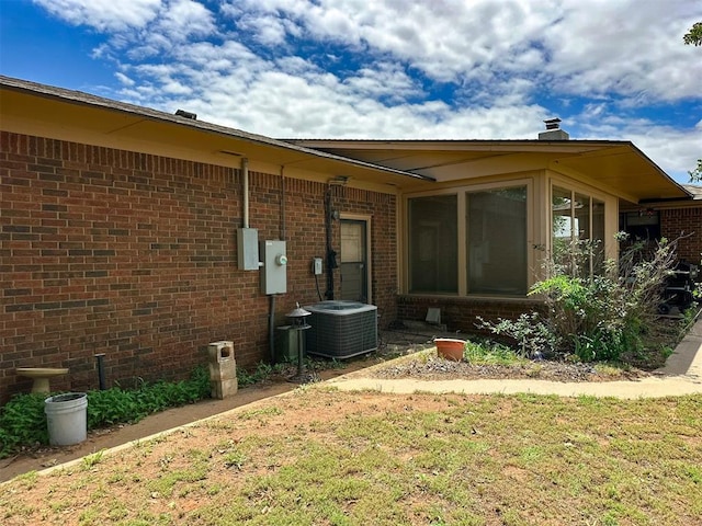 10190 County Road 1310, Fort Cobb, OK 73038 - rear view of house with central AC, a lawn, brick siding, and a sunroom
