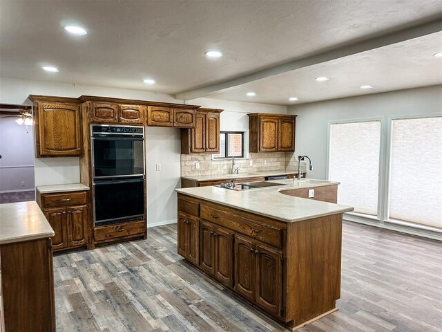 10190 County Road 1310, Fort Cobb, OK 73038 - kitchen featuring black appliances, wood finished floors, recessed lighting, a center island with sink, and decorative backsplash