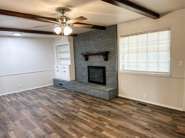 10190 County Road 1310, Fort Cobb, OK 73038 - unfurnished living room with beamed ceiling, a ceiling fan, dark wood-type flooring, a fireplace, and built in shelves