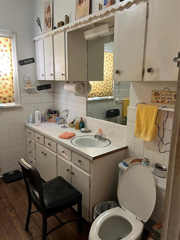 520 S Main St, Wetumka, OK 74883 - half bathroom featuring tile walls, toilet, vanity, wood finished floors, and tasteful backsplash
