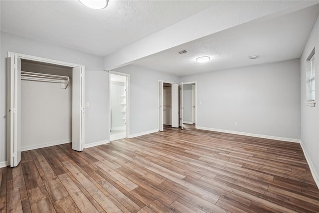 4328 NW 12th St, Oklahoma City, OK 73107 - unfurnished bedroom featuring wood finished floors, baseboards, a textured ceiling, and connected bathroom