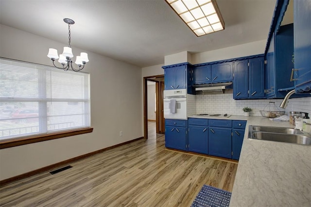 520 SE 47th St, Oklahoma City, OK 73129 - kitchen with blue cabinets, white oven, a sink, light wood-type flooring, and a chandelier