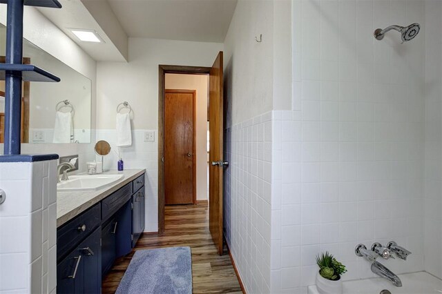 520 SE 47th St, Oklahoma City, OK 73129 - full bath with tile walls, vanity, wood finished floors, wainscoting, and shower / bath combination