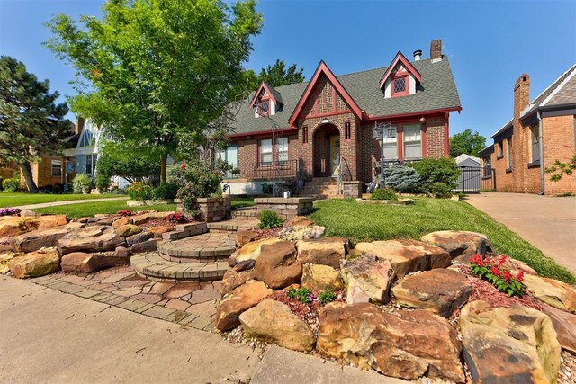 2113 N Gatewood Ave, Oklahoma City, OK 73106 - tudor house featuring brick siding, a shingled roof, and a chimney