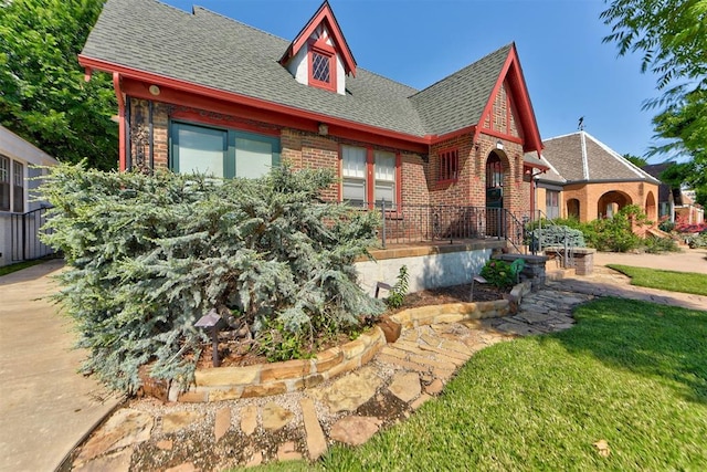 2113 N Gatewood Ave, Oklahoma City, OK 73106 - tudor-style house featuring brick siding, roof with shingles, and a front yard