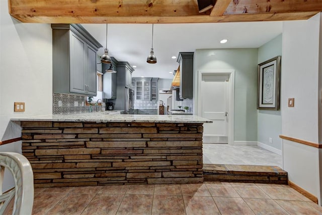 2113 N Gatewood Ave, Oklahoma City, OK 73106 - kitchen featuring gray cabinets, a peninsula, backsplash, light stone countertops, and baseboards