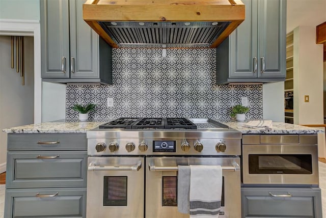 2113 N Gatewood Ave, Oklahoma City, OK 73106 - kitchen featuring range with two ovens, ventilation hood, gray cabinetry, and tasteful backsplash