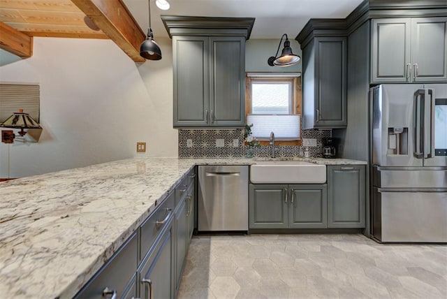 2113 N Gatewood Ave, Oklahoma City, OK 73106 - kitchen with appliances with stainless steel finishes, a sink, decorative backsplash, light stone countertops, and decorative light fixtures