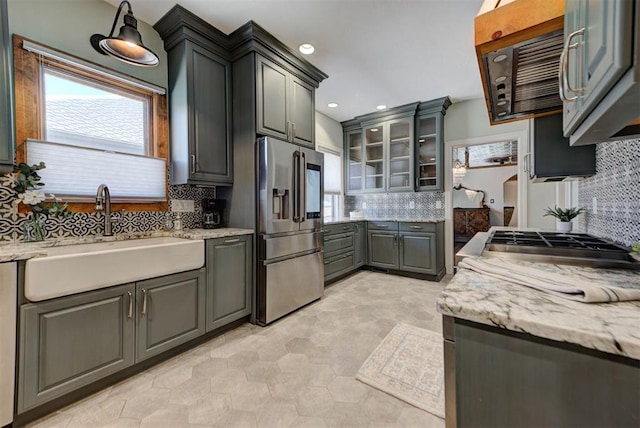 2113 N Gatewood Ave, Oklahoma City, OK 73106 - kitchen featuring stainless steel refrigerator with ice dispenser, a sink, backsplash, light stone counters, and glass insert cabinets
