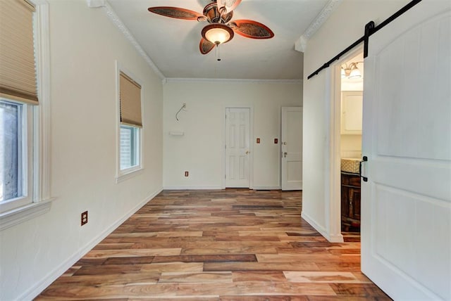 2113 N Gatewood Ave, Oklahoma City, OK 73106 - spare room with light wood-style floors, ceiling fan, a barn door, ornamental molding, and baseboards