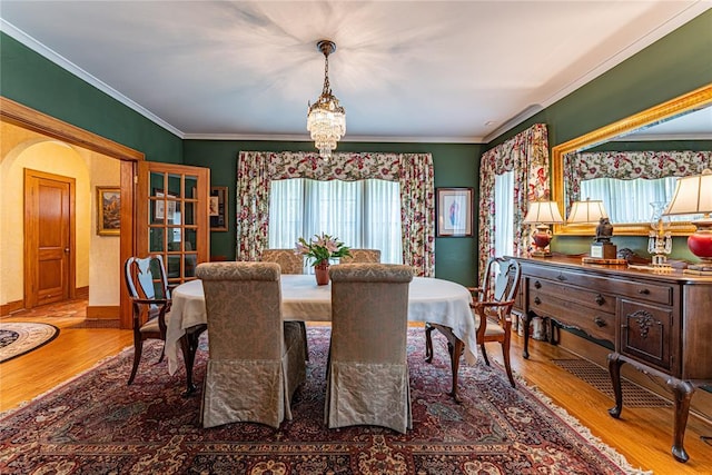 1527 NW 35th St, Oklahoma City, OK 73118 - dining space featuring wood finished floors, a chandelier, ornamental molding, arched walkways, and baseboards